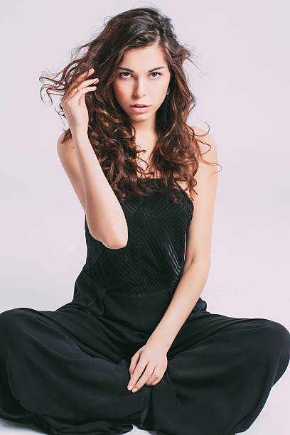 A beautiful Asian woman stands gracefully, showcasing her relaxed style in a black ensemble while expressing confidence.