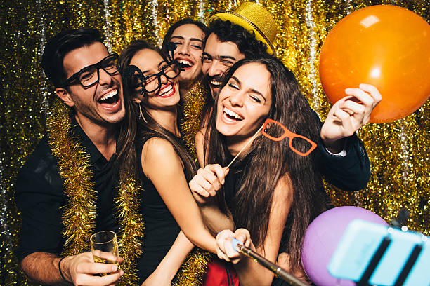 New year's selfie Friends taking a selfie  with a selfie stick while celebrating the New Year - 2016 New Year’s Eve Outfit stock pictures, royalty-free photos & images