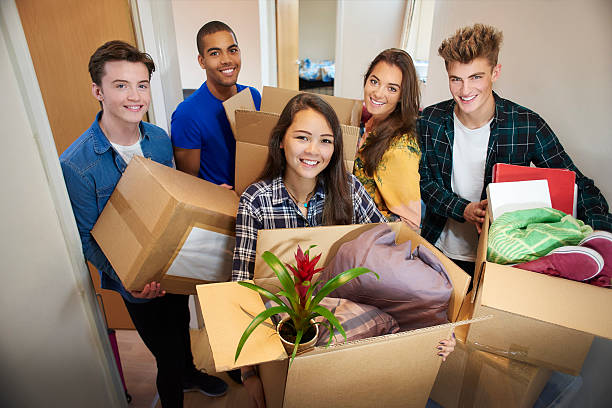 student accommodation friends A group of five university students move into their shared flat , and start to unpack boxes. they all stand and pose for the camera. college dorm photos stock pictures, royalty-free photos & images