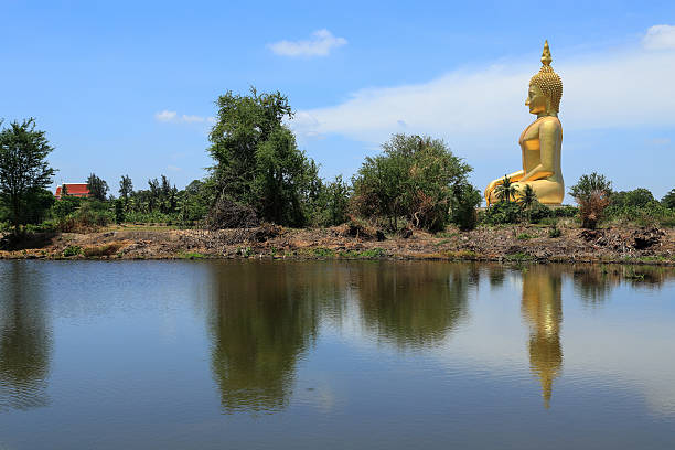 istock big  golden buddha statue sitting reflection on the water 497543237