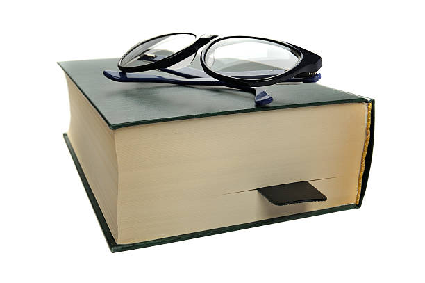 istock Reading glasses on an closed book on white background 497543558