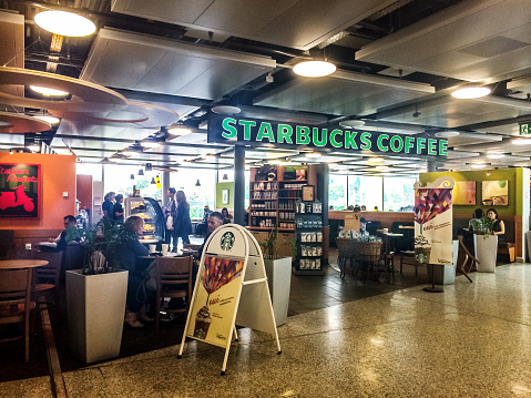 Geneva, Switzerland - May 16, 2014: People eating and drinking at Starbucks Coffee, Geneva Airport, Switzerland