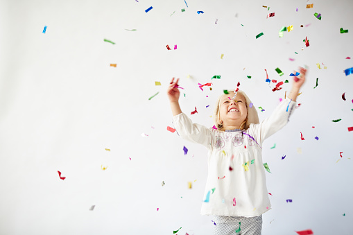 Ecstatic little girl catching falling confetti