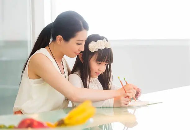 A Chinese woman and a girl work on schoolwork.