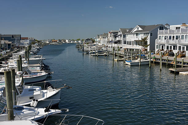 Point Pleasant Beach, USA - May 31, 2014. Waterfront houses with piers and boats and incidental man in background in Pt Pleasant Beach, New Jersey. Point Pleasant Beach is a seaside community located on the Barnegat Peninsula in Ocean County of New Jersey with a population of over 4,000. It attracts visitors with pristine beaches and a mile long boardwalk lined with places for family activities like amusement park, arcades, aquarium beside food services.