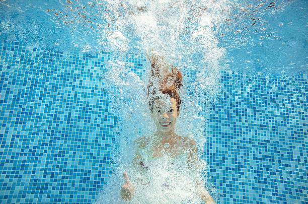 istock Girl jumps and swims in pool underwater 497547062