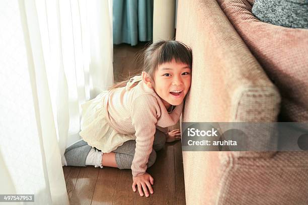 Girl Hiding Behind The Sofa Stock Photo - Download Image Now - Hide And Seek, Indoors, Asian and Indian Ethnicities