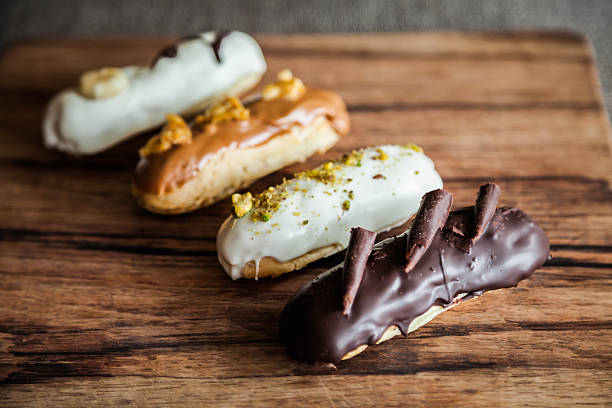 French Eclairs Four French Eclairs on a wooden board.  choux pastry photos stock pictures, royalty-free photos & images