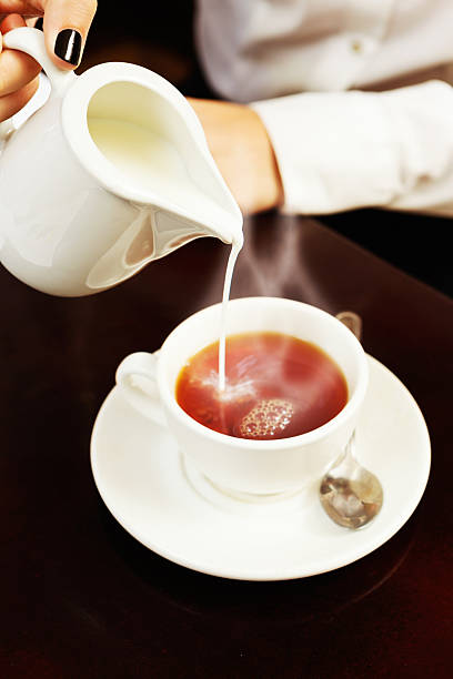 istock Have a nice cup of tea! Female hand adds milk. 497548893