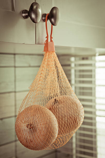 istock Vintage Onions in mesh bags hanging on the kitchen 497550565