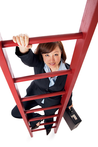 This is a photo of an Asian business woman climbing a red ladder isolated on a white background.