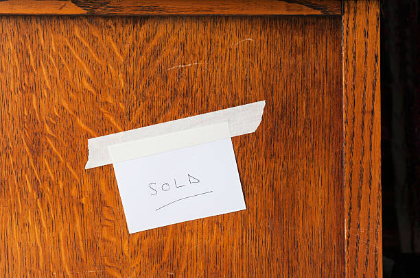Close up of a sticker saying 'Sold' on the side of a piece of wooden second hand furniture (dressing table).