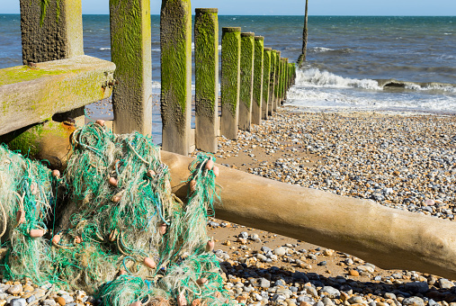 A discarded fishing net from a trawler that has been washed onto the beach and become tangled with the sea groyne causing a danger to users of the beach and birds