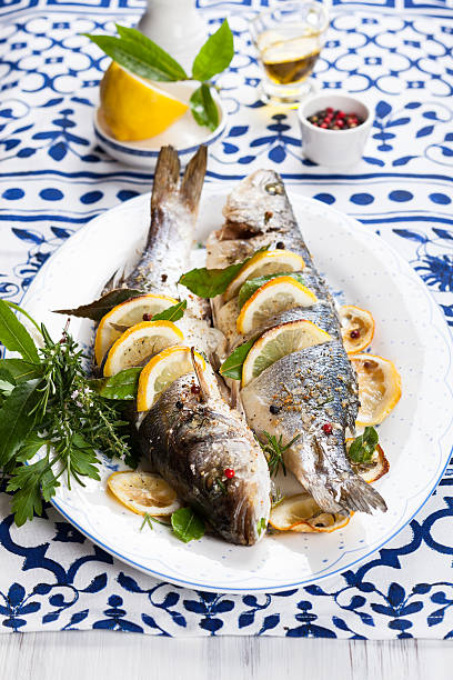 Oven-baked Sea bass Oven-baked Sea bass with lemon and herbs daequan cook stock pictures, royalty-free photos & images