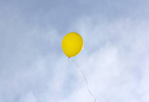 istock Yellow balloon flying on a blue sky background 497572628