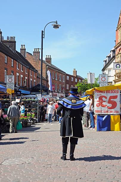 Town crier and market, Tamworth. Tamworth, United Kingdom - May 17, 2014:  Town Crier standing on the edge of the street market in the centre of town, Tamworth, Staffordshire, England, UK, Western Europe. town criers stock pictures, royalty-free photos & images