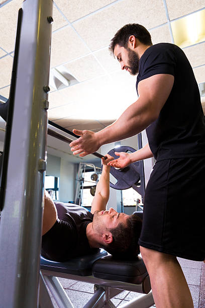 istock Bench press weightlifting man with personal trainer 497585115