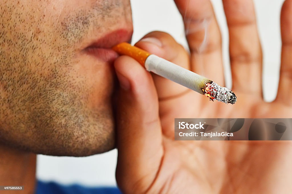Close up portrait of young man smoking cigarette Man smoking cigarette on white background Abuse Stock Photo