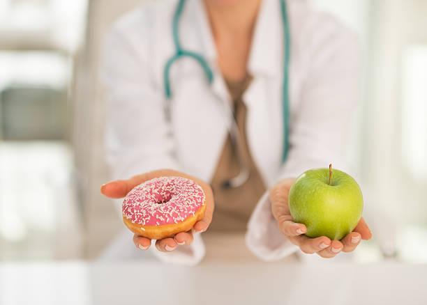 gros plan sur le médecin donnant le choix entre apple et donut - diabetes food photos et images de collection