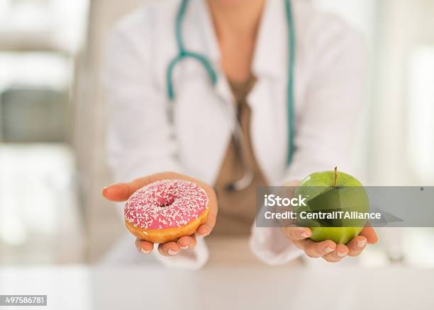 Closeup On Doctor Giving A Choice Between Apple And Donut Stock Photo - Download Image Now