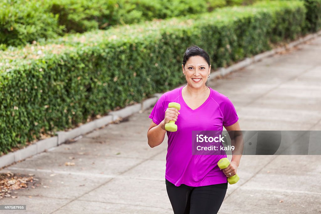 Hispanic woman exercising in park Hispanic woman (30s) power walking in the park. 30-39 Years Stock Photo