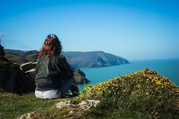 istock Young woman sitting on edge of cliff 497598263