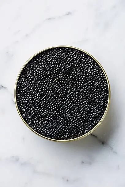 Sturgeon black caviar in can on white marble background