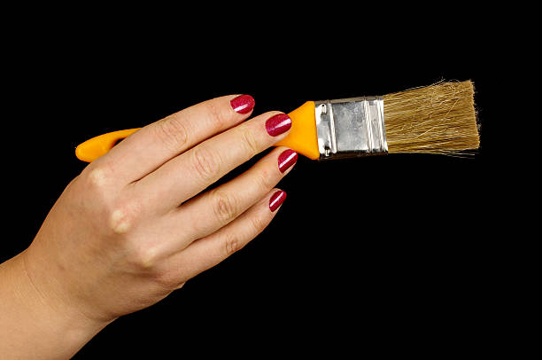 istock Female hand holding paintbrush isolated on the black background 497602013