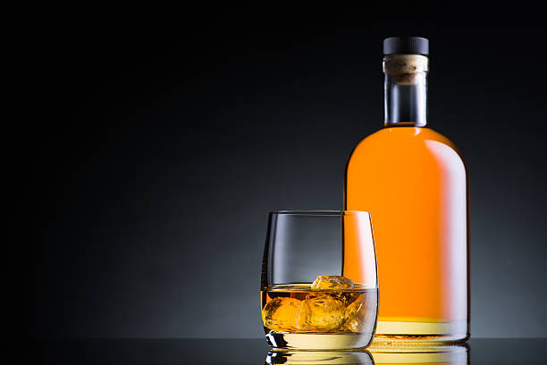 istock Whiskey glass and bottle on black glass surface 497602536