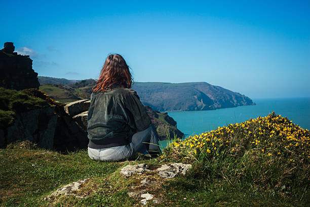 istock Young woman sitting on edge of cliff 497602595