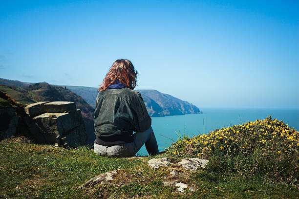 istock Young woman sitting on edge of cliff 497602599