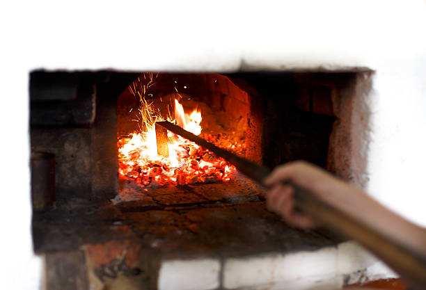 Stir the coals in the stove with a poker, selective focus