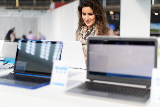 Choosing laptop Woman choosing laptop in electronics store computer shop stock pictures, royalty-free photos & images