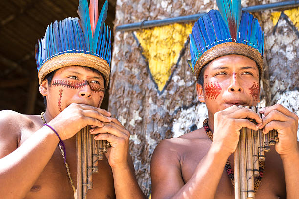 istock Native Brazilian guys playing wooden flute 497609390
