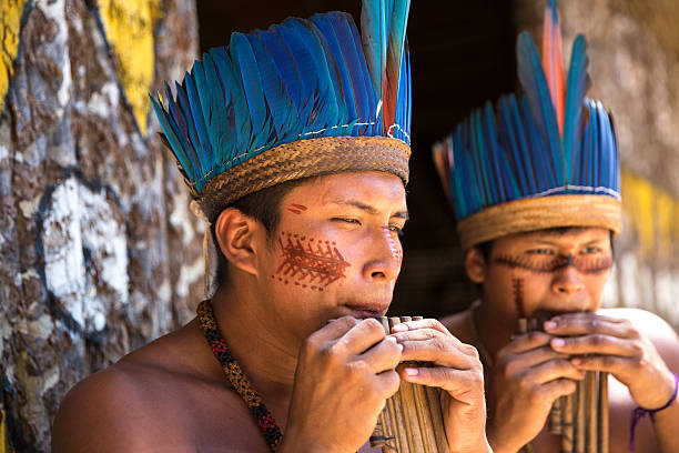 istock Native Brazilian guys playing wooden flute 497609462