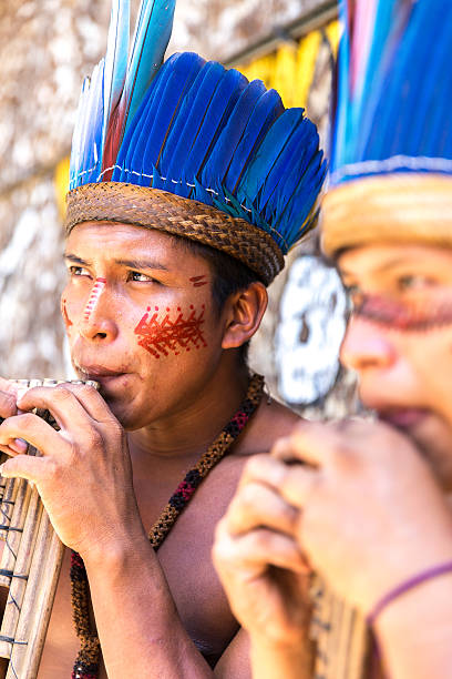 istock Native Brazilian guys playing wooden flute 497610518