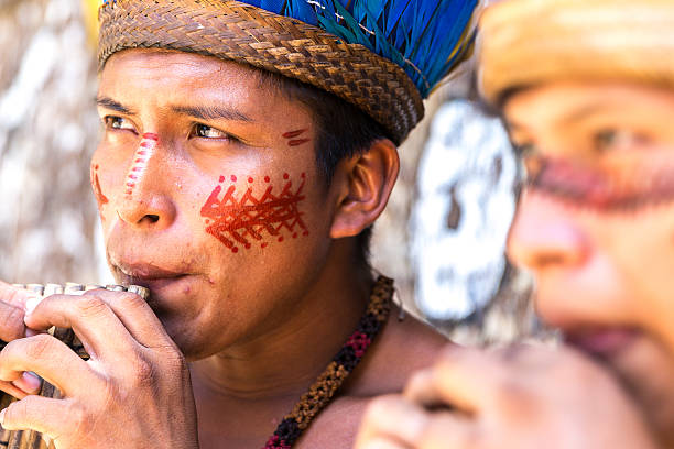 istock Native Brazilian guys playing wooden flute 497610572