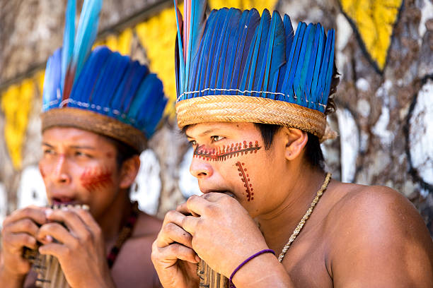 istock Native Brazilian guys playing wooden flute 497610648