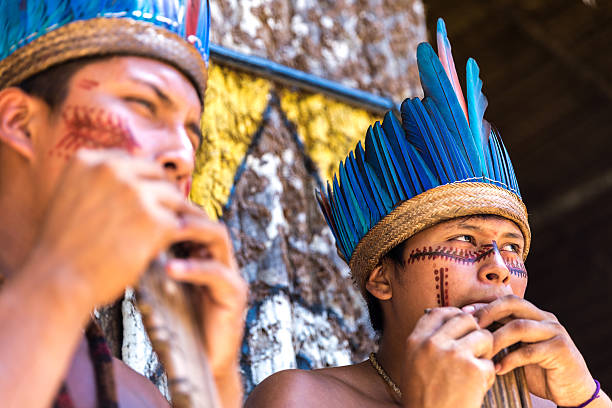 istock Native Brazilian guys playing wooden flute 497610996