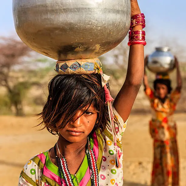 Photo of Indian little girls carrying on their heads water from well