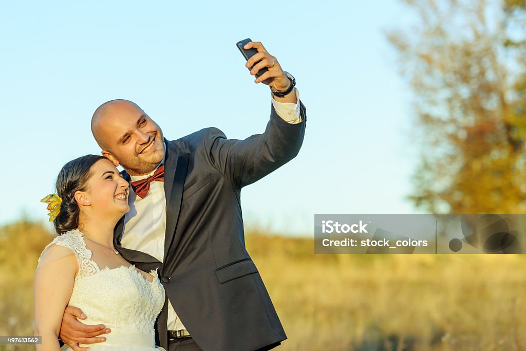 capturing beautiful moments portrait of bride and groom outdoors, embracing and smiling.self portrait photography with their phone.autumn day. 20-29 Years Stock Photo