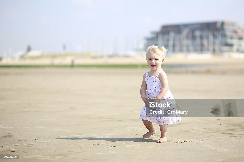 Bebê Menina em lindo vestido caminhando ao longo da praia - Foto de stock de Bebê royalty-free