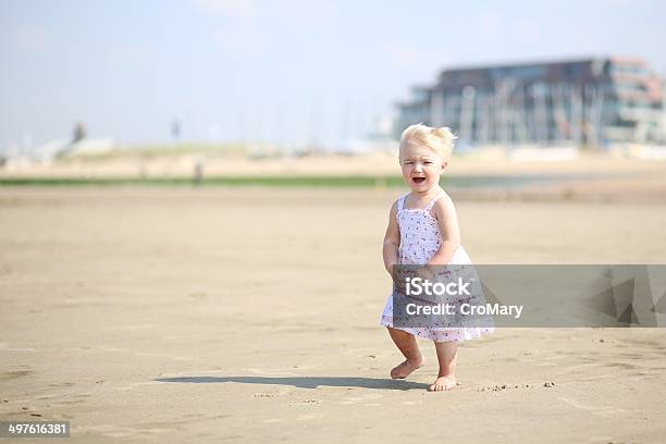 Foto de Bebê Menina Em Lindo Vestido Caminhando Ao Longo Da Praia e mais fotos de stock de Bebê