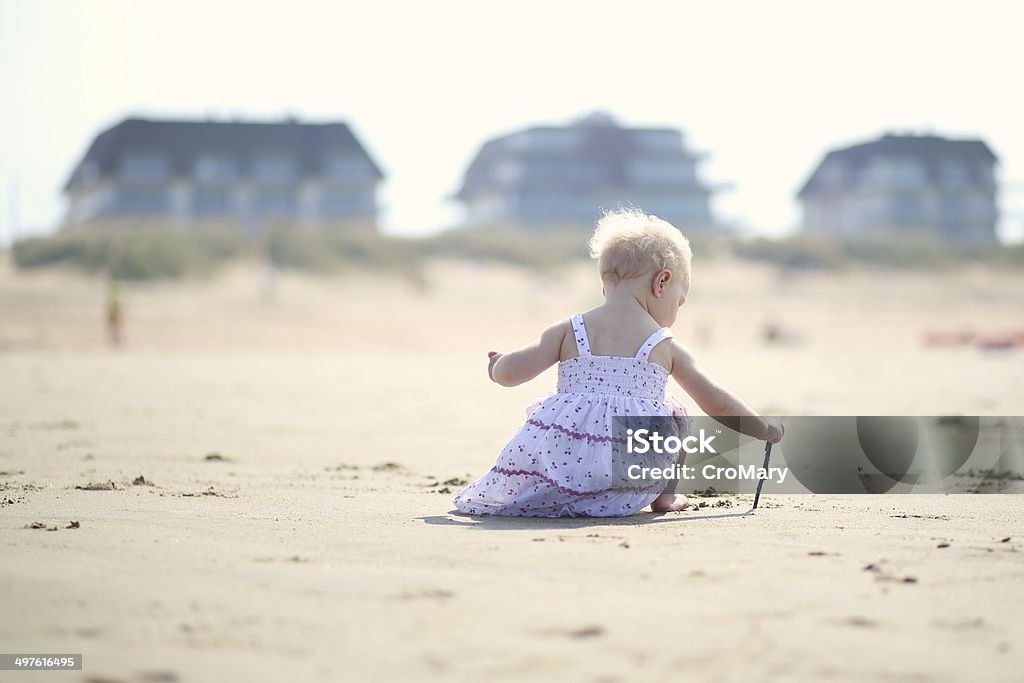 Bebê Menina em um vestido bonito brincando na praia - Foto de stock de 12-17 meses royalty-free