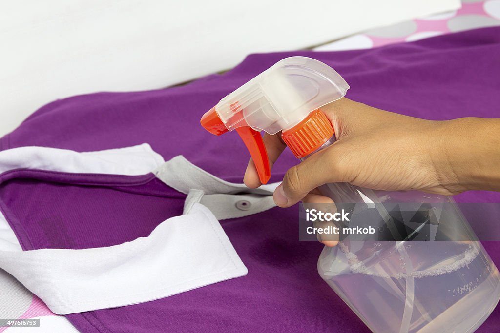 Spraying a casual cloth with laundry detergent in spray bottle. Spraying a casual shirt with laundry detergent in spray bottle. Bottle Stock Photo