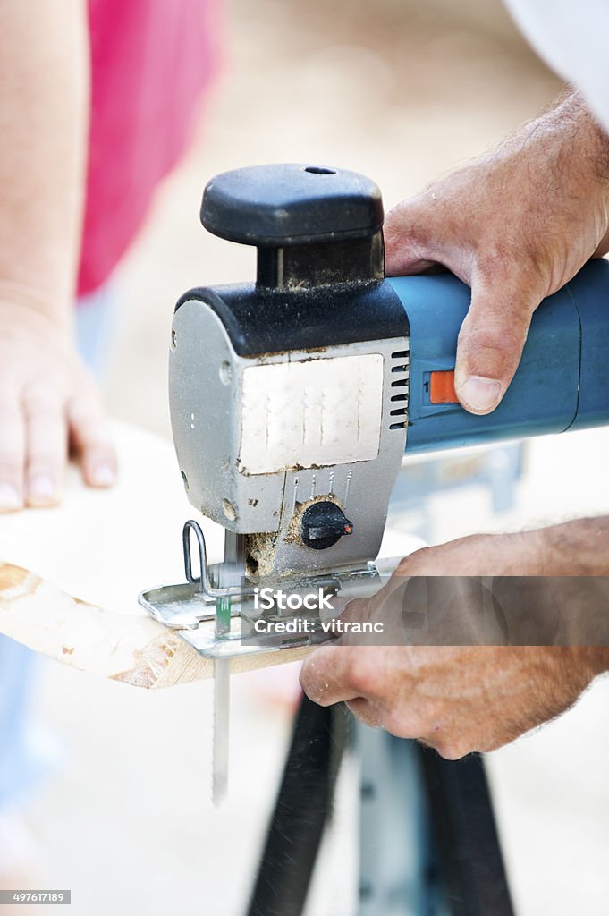 Man with jigsaw cutting a plank Man with jigsaw cutting a plank. Close-up shot of hands and jigsaw Accuracy Stock Photo