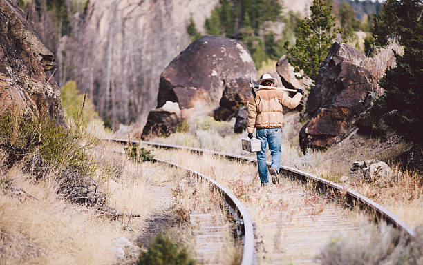 istock Man walks down railroad tracks carrying tools and looking down 497618429