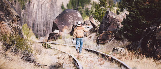 istock Hard working man walks down railroad tracks carrying pickaxe 497618431
