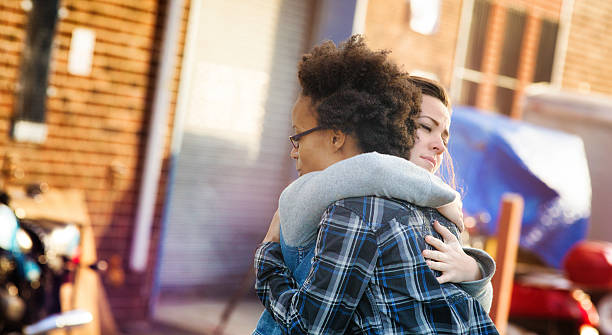 Young women forgiving each other with a hug Young women forgiving each other with a hug in an alley. Tthey are both dressed in casual urban clothing. Photographed at sunset in Brooklyn. Letterbox format. forgiveness stock pictures, royalty-free photos & images