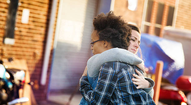 Young women forgiving each other with a hug Young women forgiving each other with a hug in an alley. Tthey are both dressed in casual urban clothing. Photographed at sunset in Brooklyn. Letterbox format. mercy hug stock pictures, royalty-free photos & images
